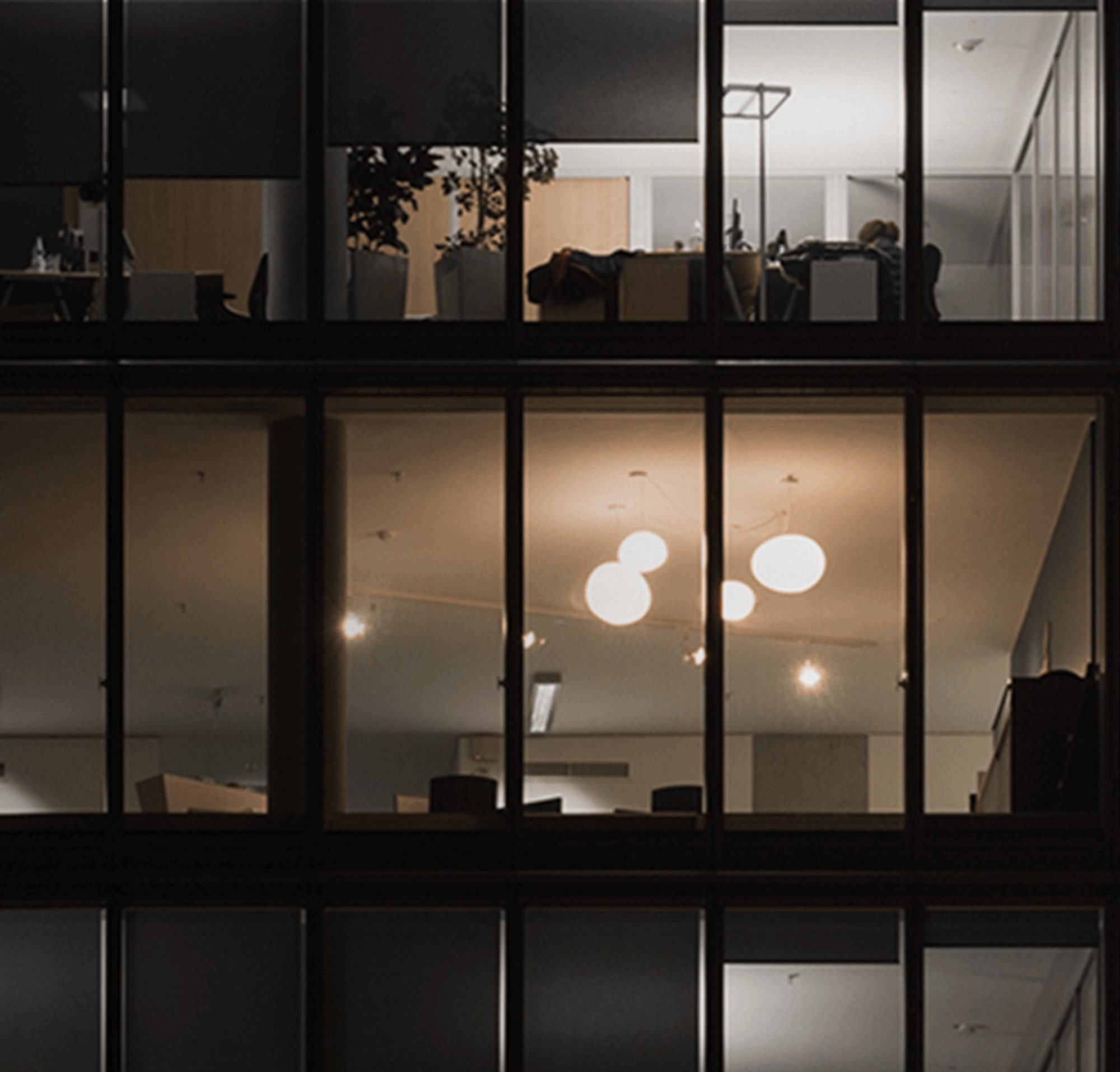 Una imagen de tres pisos en su mayoría oscuros en un edificio de oficinas de varios pisos por la noche.